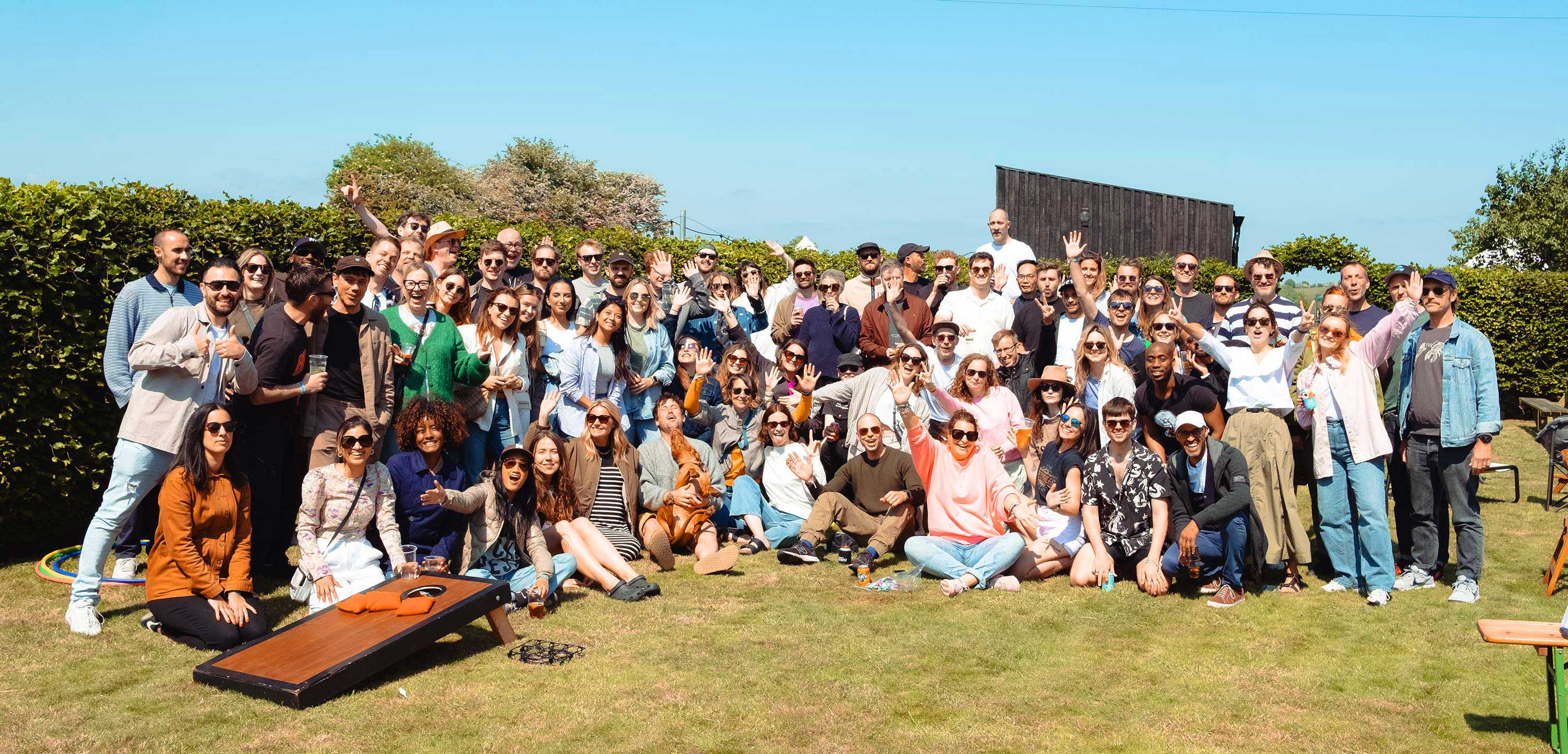 A group photo of employees at our annual social day, smiling, waving and cheering